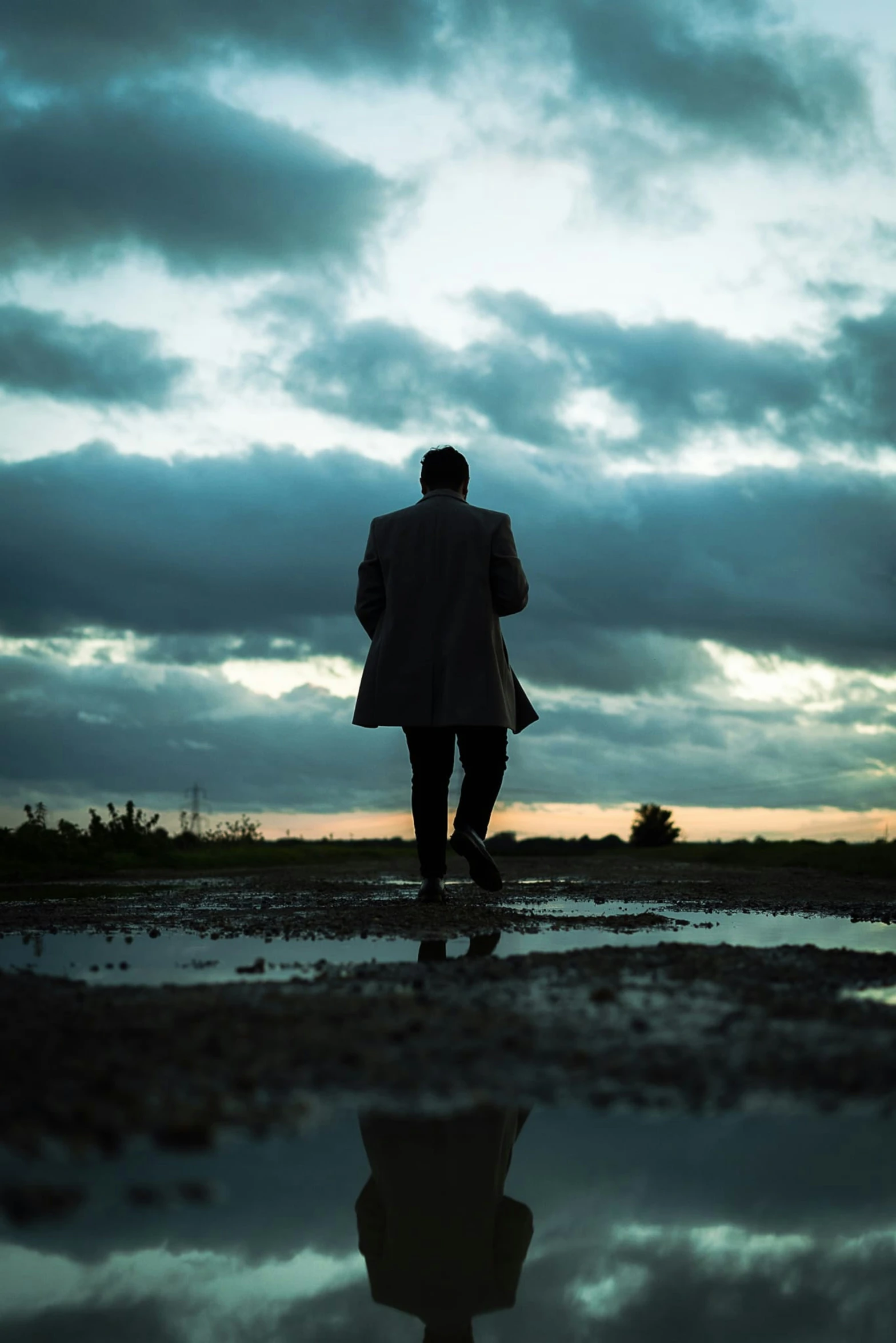 a man is walking alone with his reflection in the wet mud