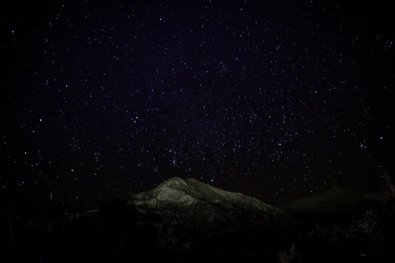 a night time s of the mountains with stars all over