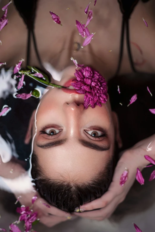 woman has her face pressed into flowers by a man with a cat