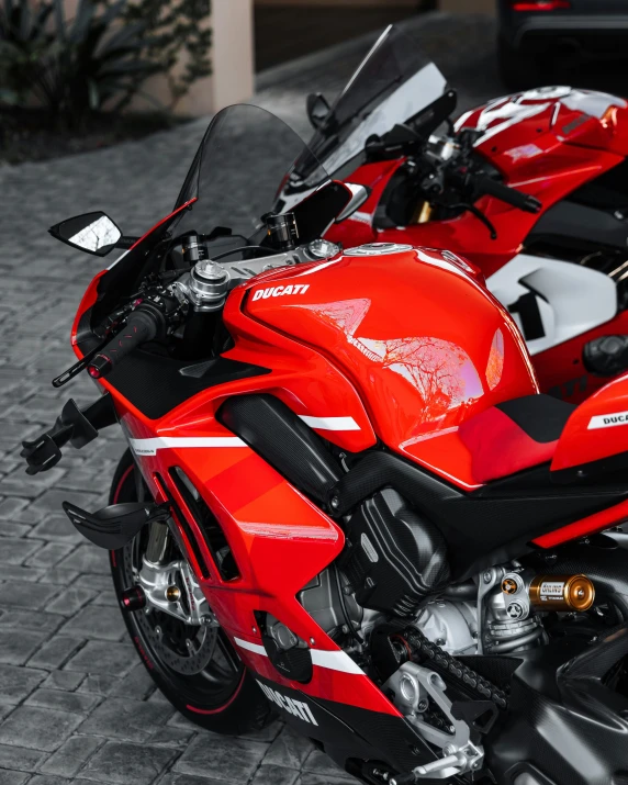 a red and black motorcycle parked on top of a brick road