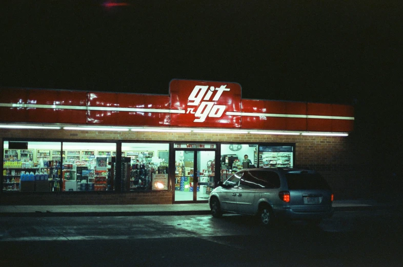 a car parked in front of a store lit up at night