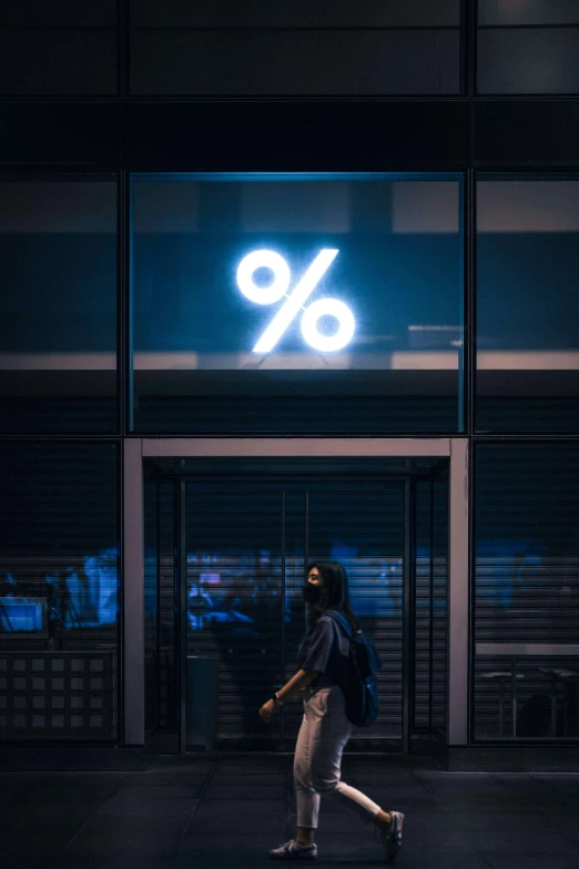 a person walking past a dark building that has a sign that reads 90