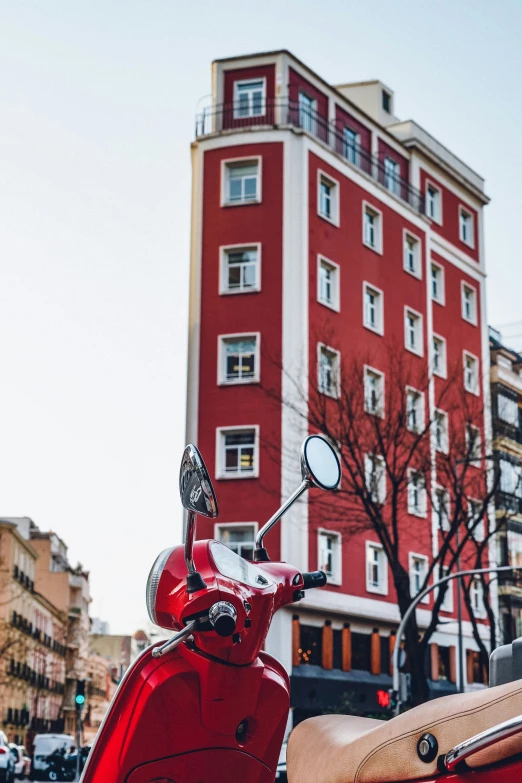 a red motorcycle parked on a street in front of a tall red building