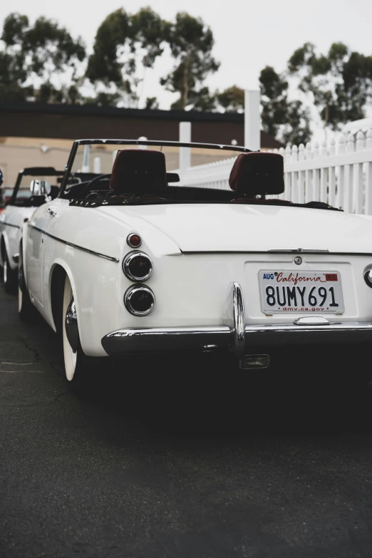 two vintage convertibles parked next to each other in a parking lot