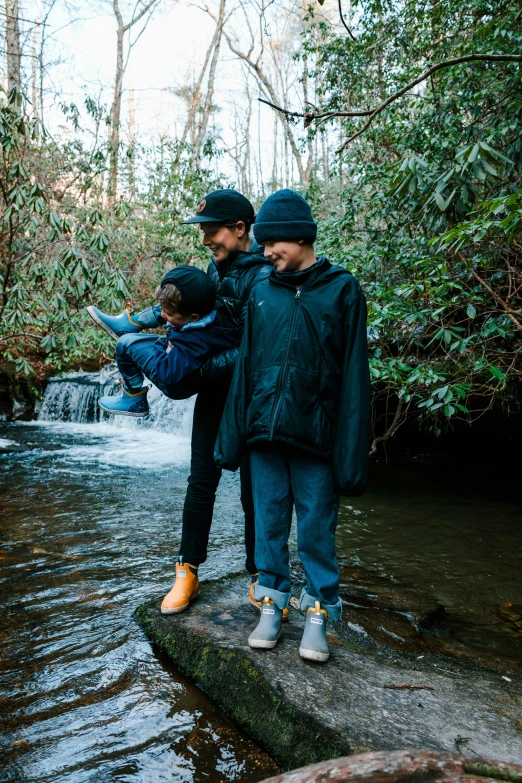 three people stand on a rock in the water