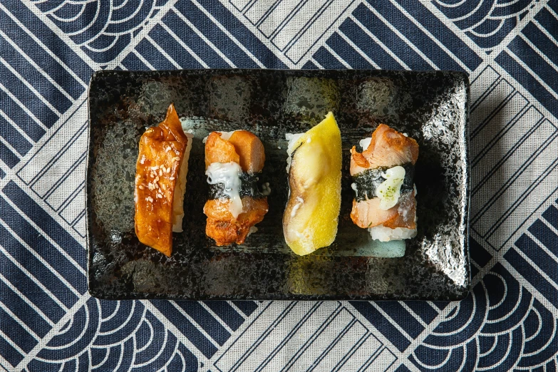 four sushi rolls sit on a tray with a side of sliced fruit