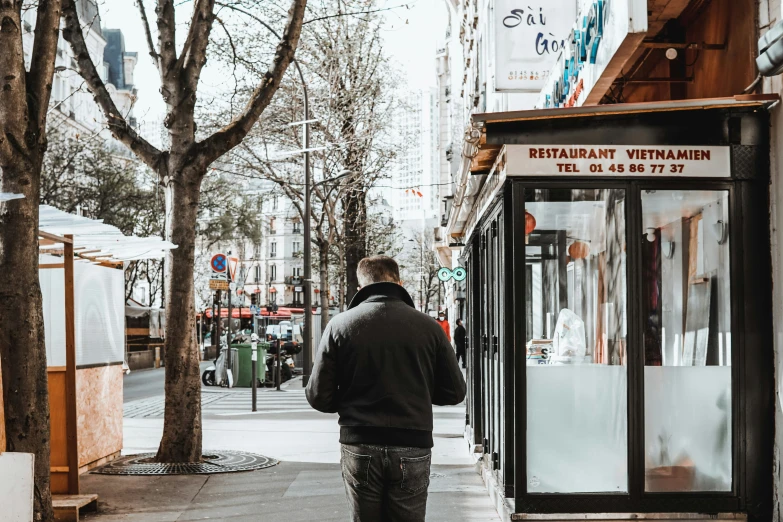 a man walking down a street past a closed store