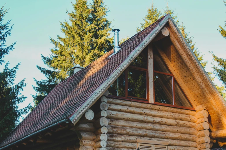 the wooden cabin has lots of windows, a chimney, and wood