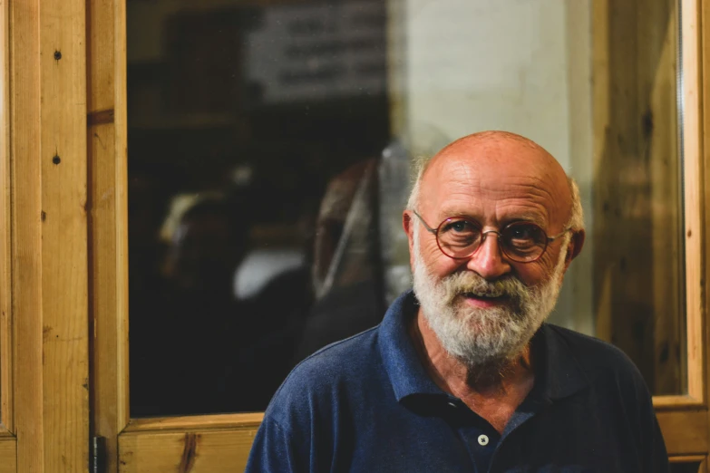 an older man is smiling in front of a window