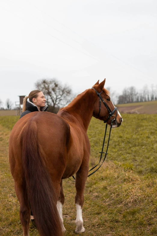 a woman in a jacket and boots riding on a horse