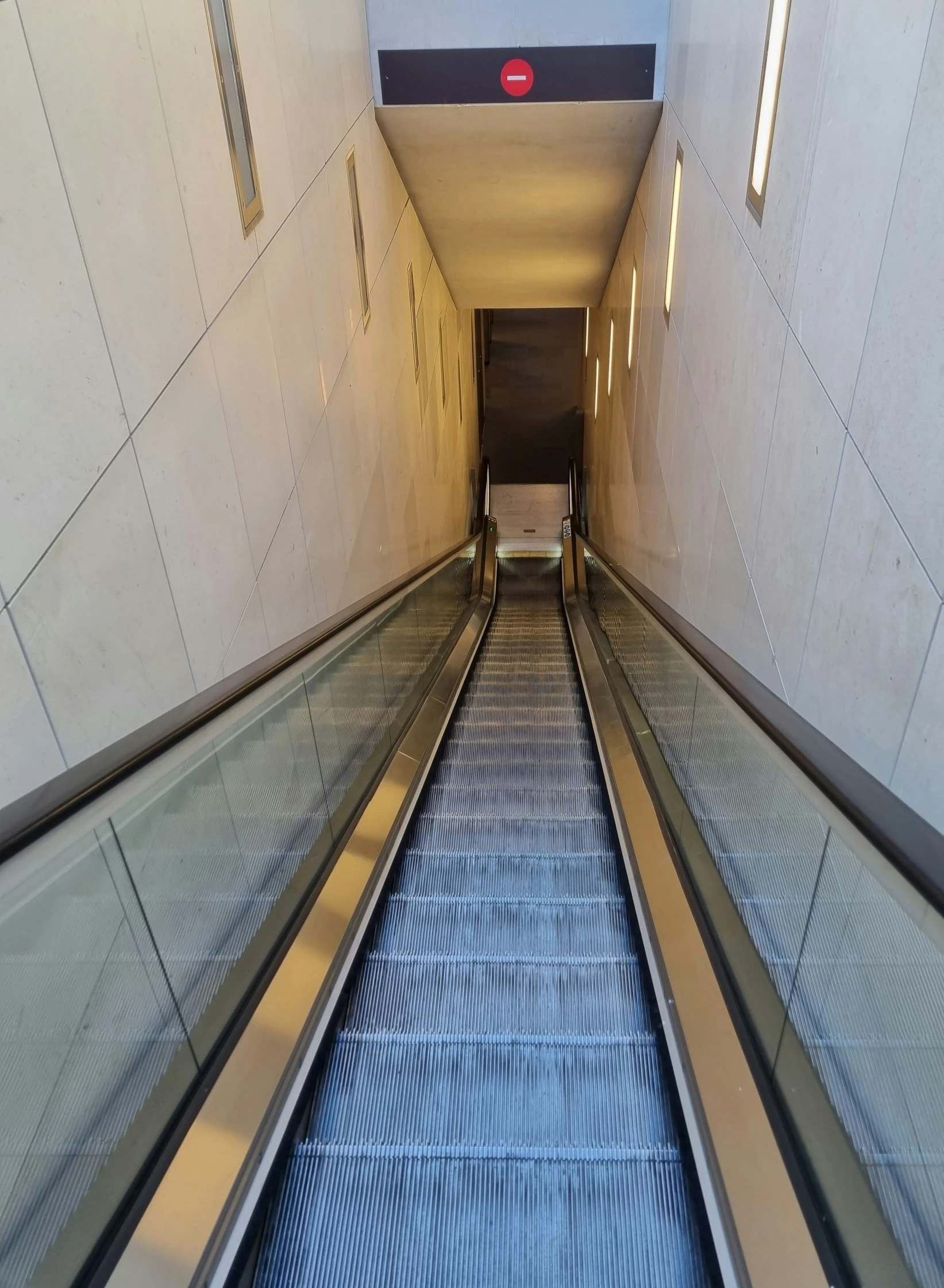 an escalator with glass divider next to a chair