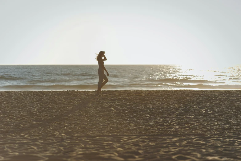 the silhouette of a woman standing on the beach