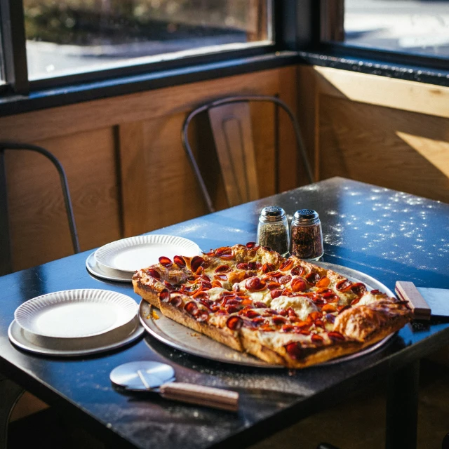 a table with two plates, some white dishes and a pizza on it