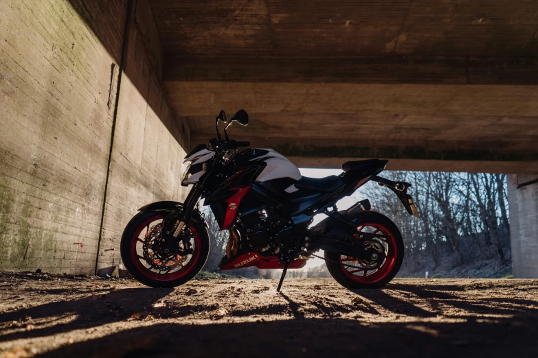 a motorcycle parked on dirt under a large bridge