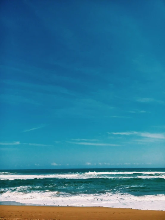 a sandy beach with blue water and waves