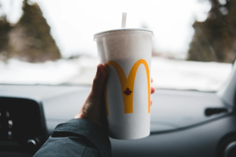 a person holding up a cup of mcdonald's coffee