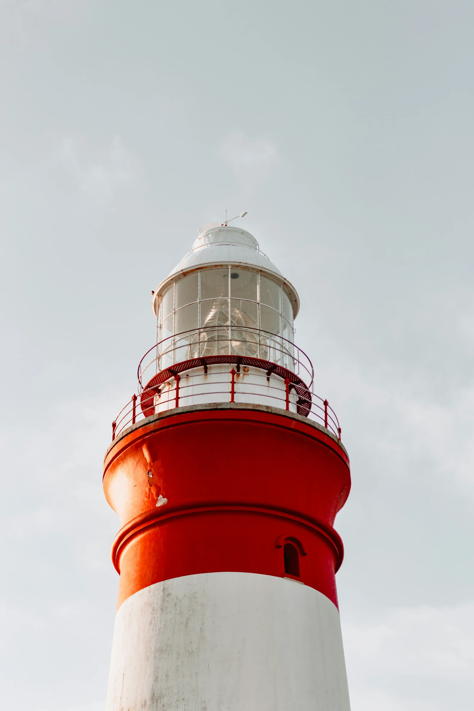 a red and white light house against a sky background