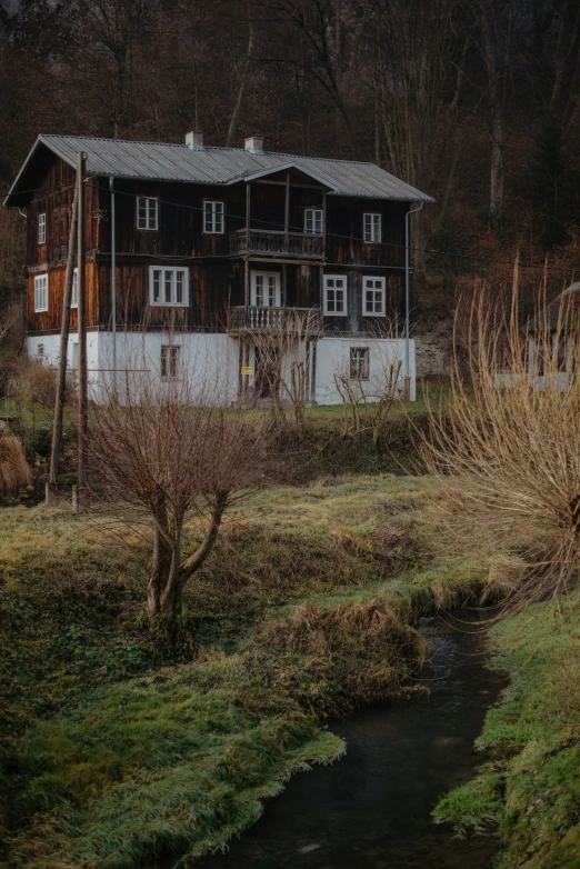 a small creek running past two houses on the side of a hill