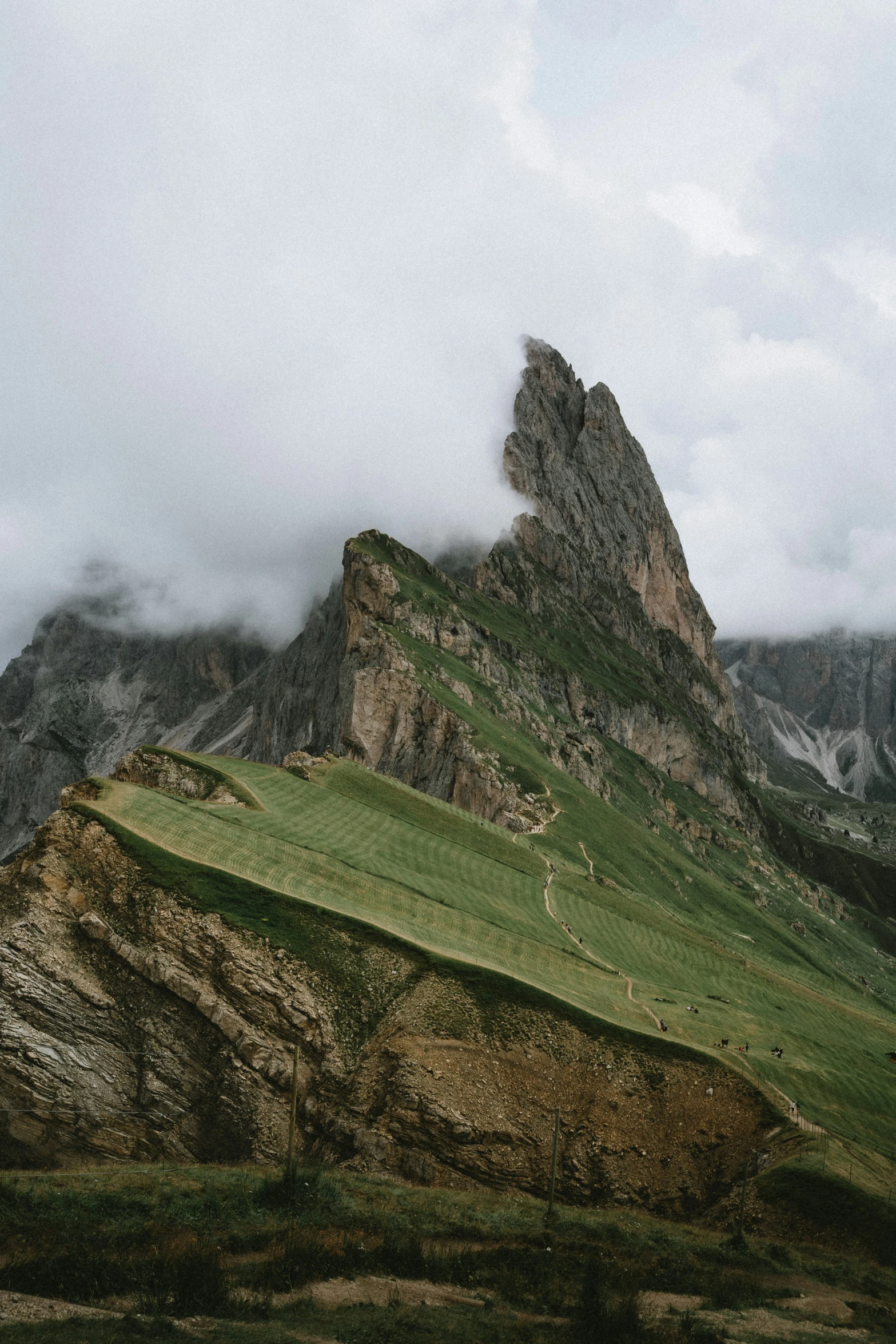 a large green mountain with mountains and clouds