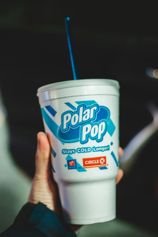 a hand holding up a cup that has a lid and straw in it