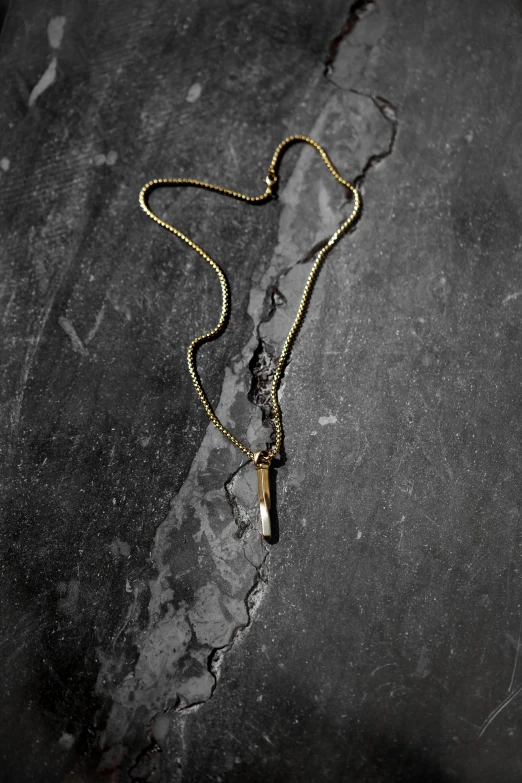 a long ss chain is hanging from a small cross necklace