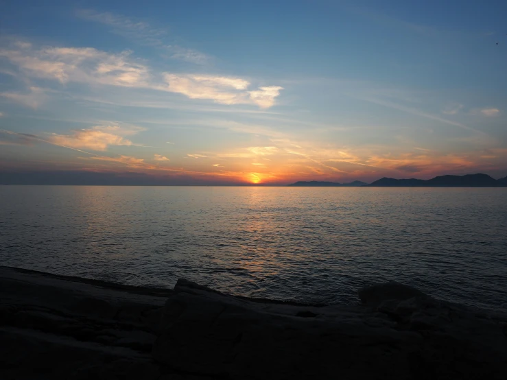 the sun sets over a calm ocean on a sunny day