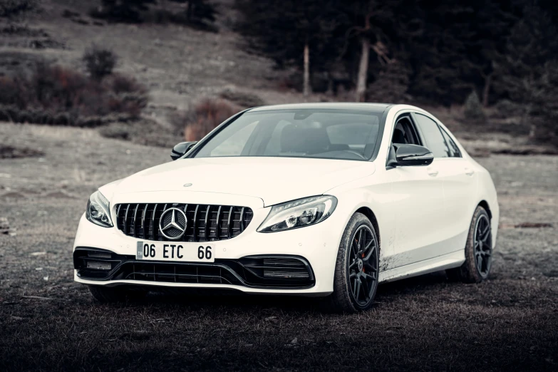 the mercedes benz c - class in white sitting on top of a dirt ground