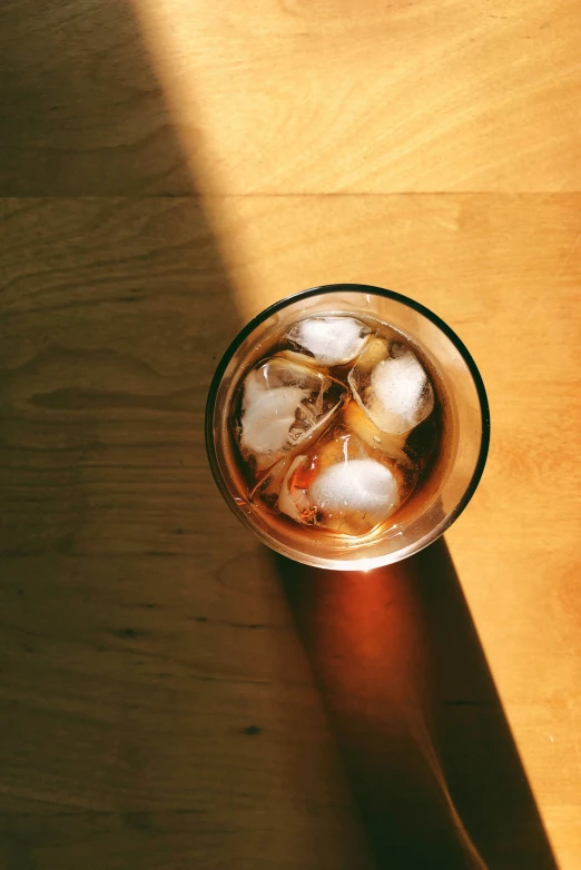 a glass with some ice on top of a wooden table