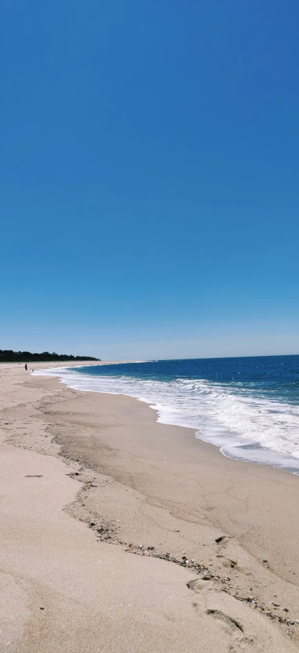 a person walking on the sand of a beach next to the ocean