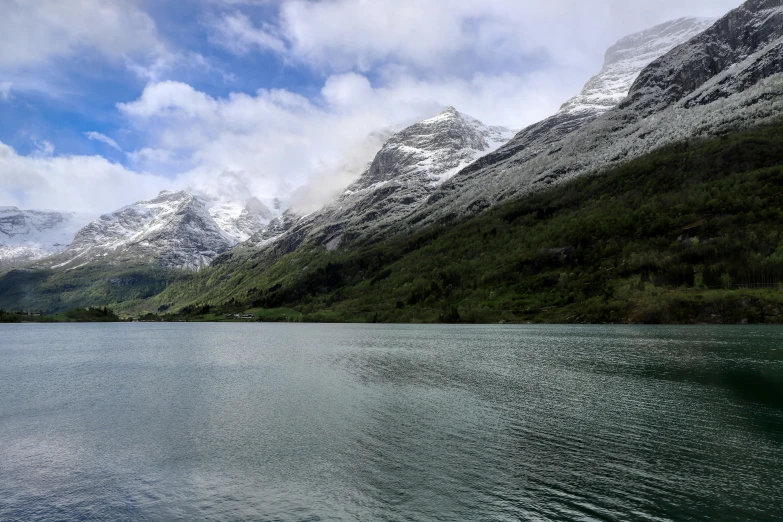 a body of water surrounded by mountains and clouds