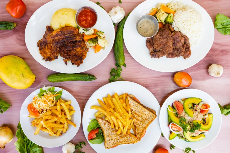 plates of food on the table include fries, pasta, meat and vegetables