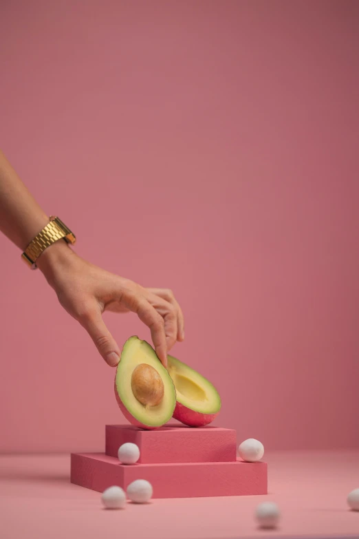 a person slicing an avocado on a pink surface