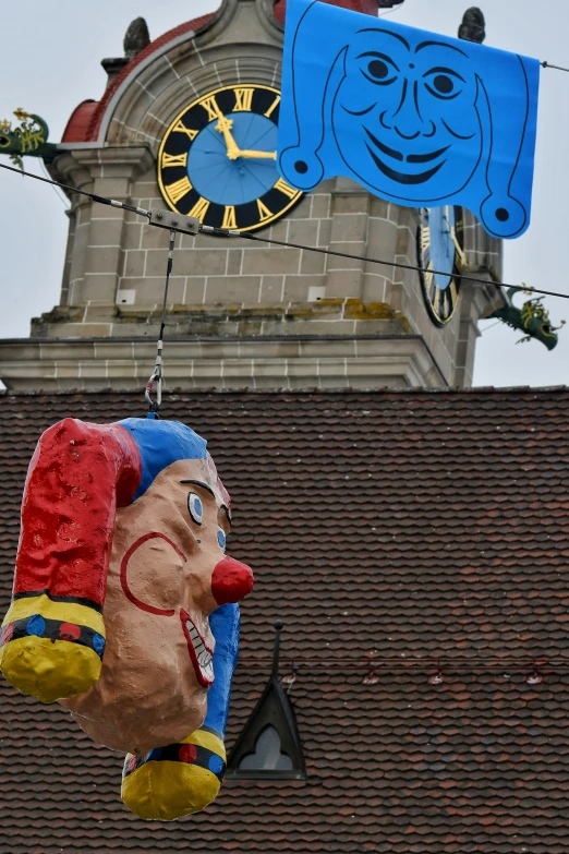 two large plastic clown figures hanging from a building's roof