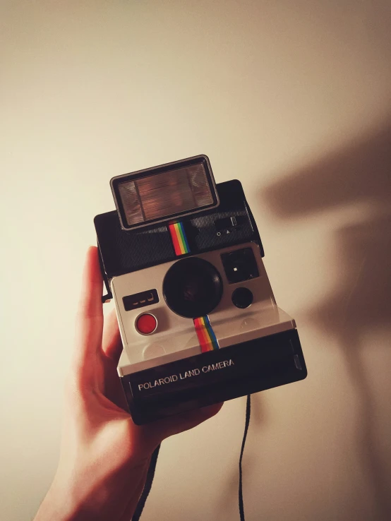 someone holding up a polaroid in the air with an object