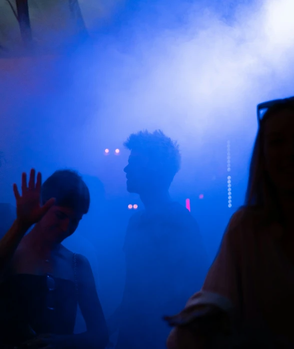 people in the dark standing on a stage with smoke coming from them