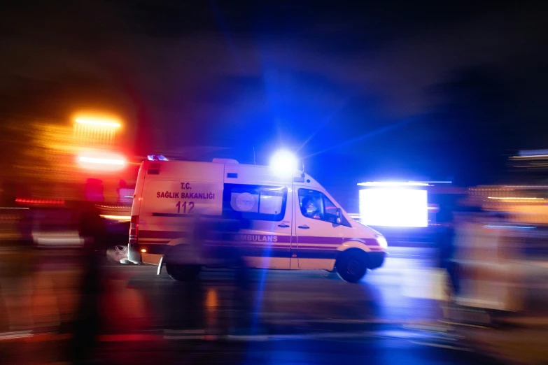 an ambulance is traveling down a street in the rain