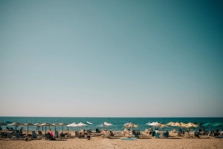 people sitting on chairs on the beach while others walk