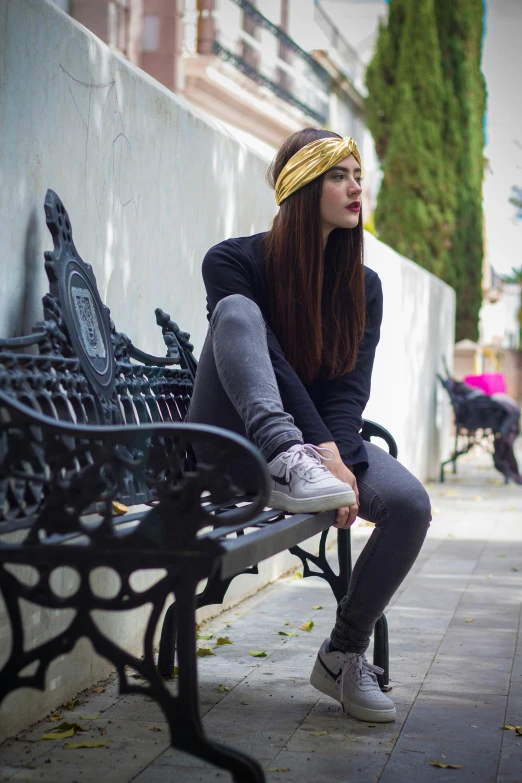 a beautiful young woman sitting on top of a metal bench