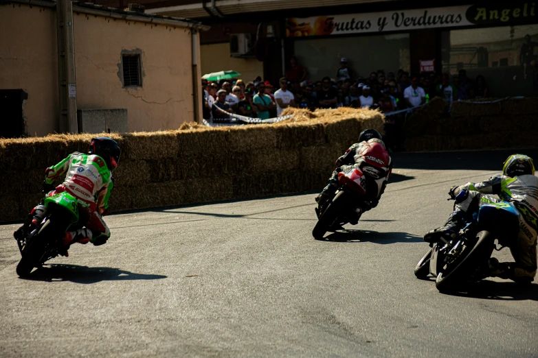 a couple of men on motorcycles riding in front of a crowd