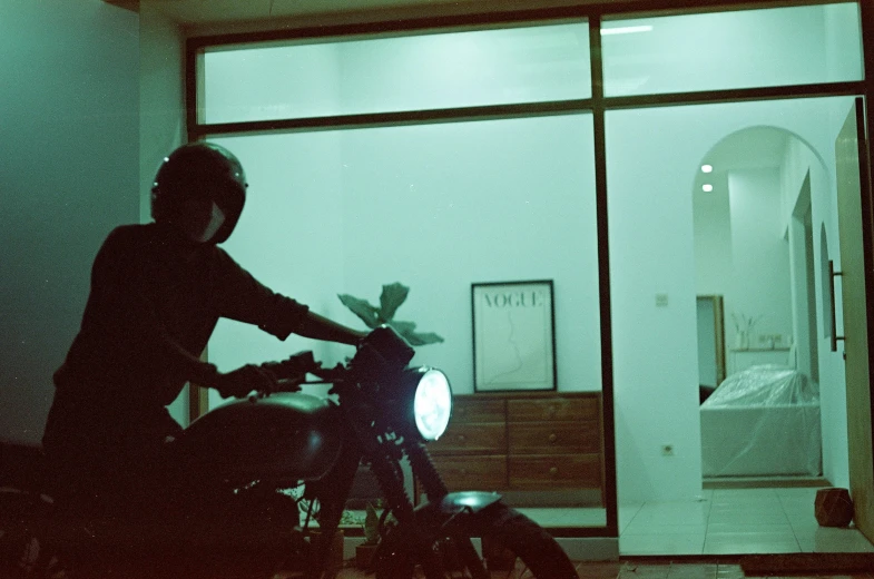 person on motorcycle parked outside of window at night