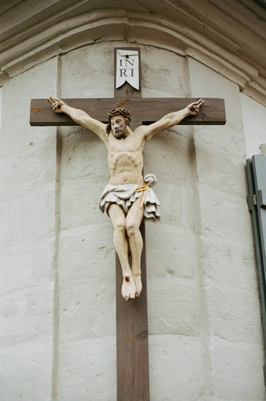 a statue of christ on the cross against a church wall