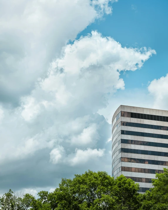 a tall building sitting between two trees and some clouds