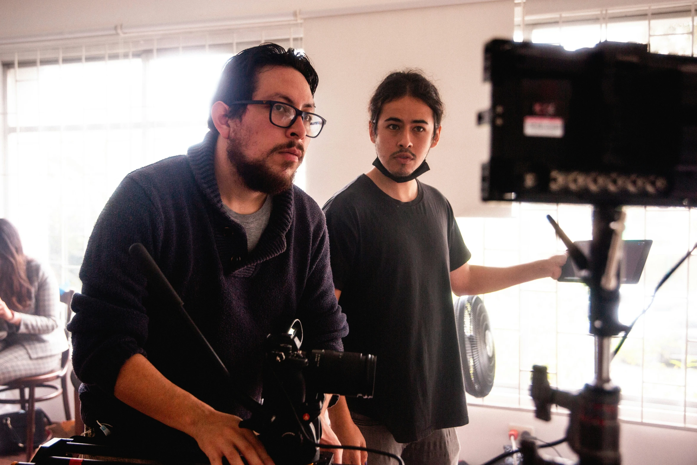 a man that is sitting down next to a camera