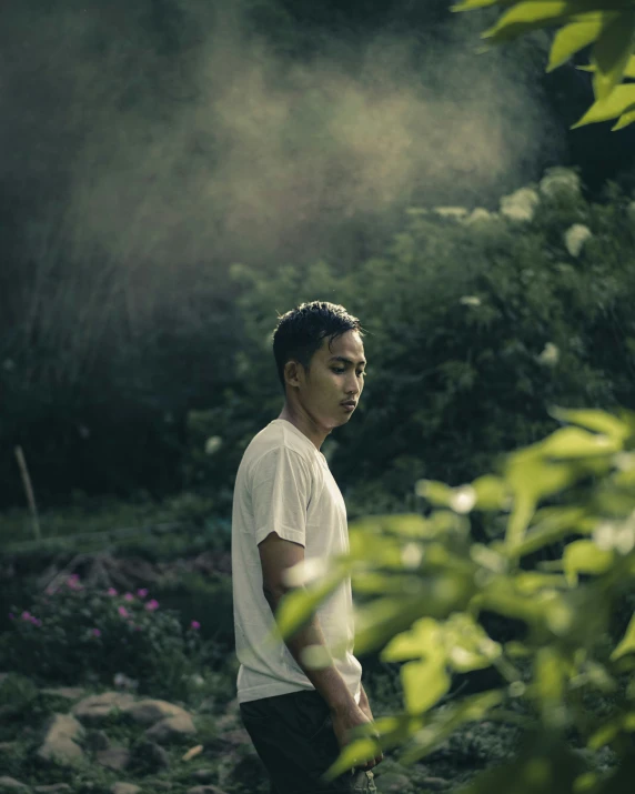 a man wearing a white shirt standing in the woods