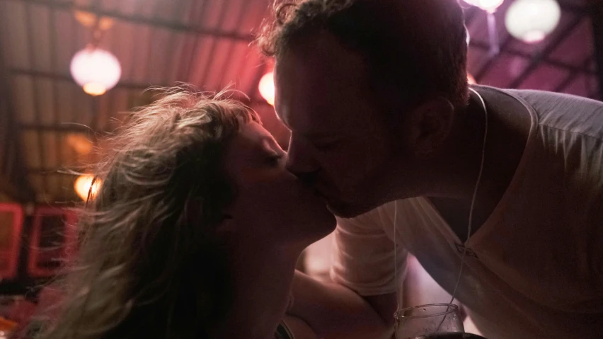 a woman and man kissing in a room with lights