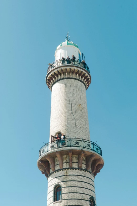 a white brick tower with people standing on top