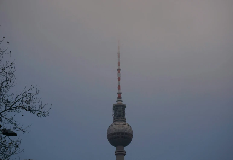 a tv tower is shown from far away on a cloudy day