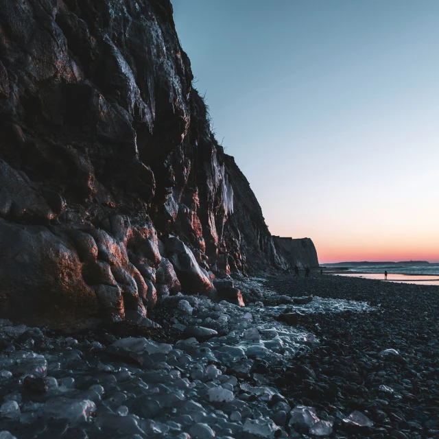 some rocks are on the beach by the water