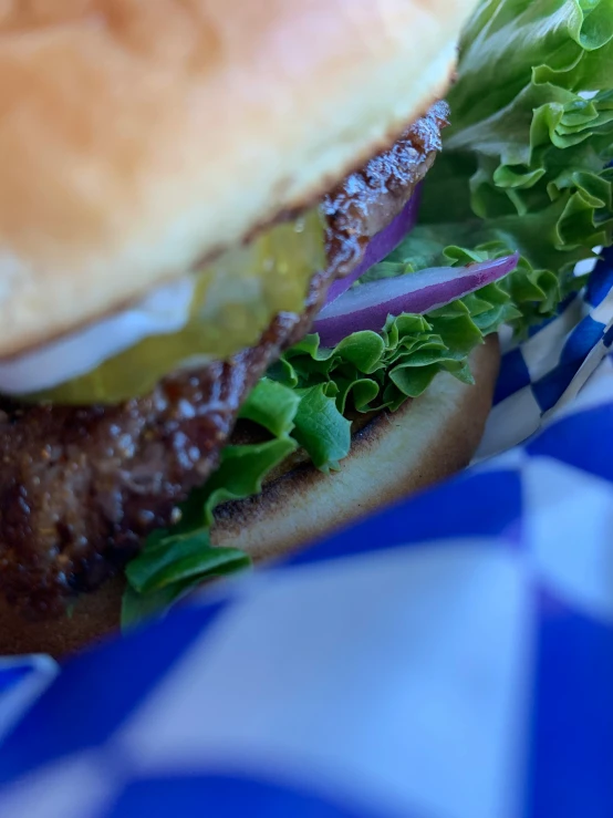 an elaborate burger sitting on top of a checkered paper table cloth