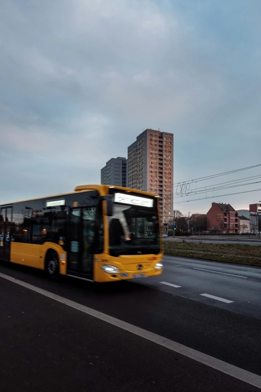 a yellow city bus is driving down the road